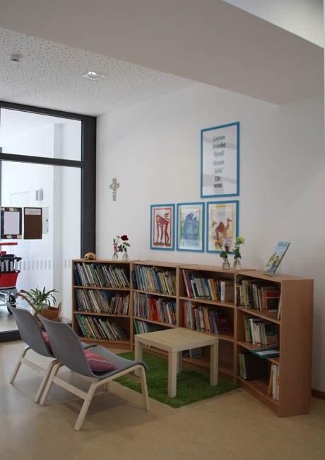 Unsere Leih-Bücherei lädt zum Lesen und Verweilen ein Eine gemütliche Leseecke im Flurbereich der KiTa mit einem Bücherregal und einer Sitzgelegenheit.