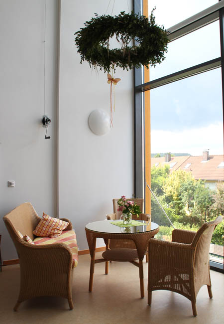 Die offene Galerie – ein Ort der Begegnung in der KiTa St. Marien Eine helle Sitzgruppe in der offenen Galerie mit großer Fensterfront und Blick nach draußen.